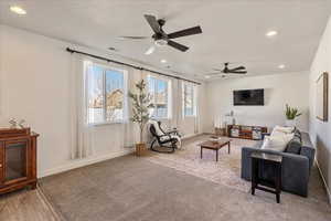 Carpeted living room with recessed lighting and ceiling fan