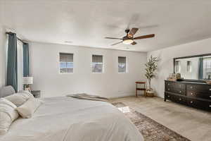 Bedroom featuring light carpet, a ceiling fan, multiple windows, and a textured ceiling