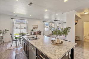 Kitchen featuring open floor plan, light countertops, dark wood-style flooring, an island with sink, and recessed lighting