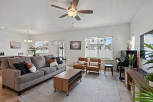 Living area with ceiling fan, a chandelier, and light wood-style flooring