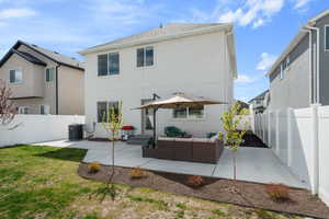 Back of property featuring an outdoor living space, a patio area, a fenced backyard, and stucco siding