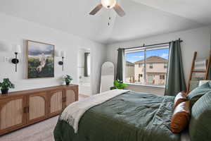 Bedroom with vaulted ceiling, light carpet, ensuite bathroom, and ceiling fan