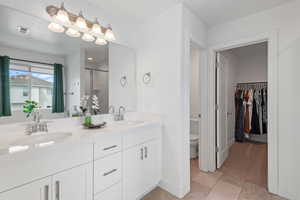 Bathroom with double vanity, a stall shower, and a spacious closet
