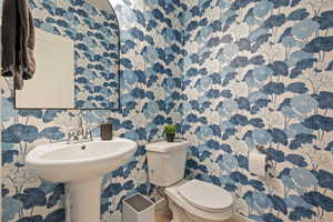 Half bath with toilet and wallpapered walls