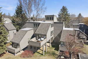 Rear view of property with a wooden deck, a shingled roof, a sunroom, a gambrel roof, and a residential view