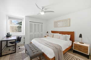 Bedroom featuring light wood-style floors, a desk, a closet, and a ceiling fan
