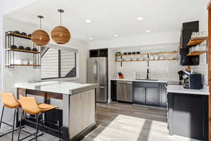 Kitchen with open shelves, a kitchen bar, stainless steel appliances, and tasteful backsplash