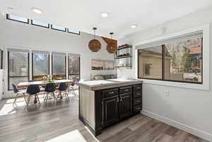 Kitchen featuring a peninsula, hanging light fixtures, dark cabinets, plenty of natural light, and a high ceiling