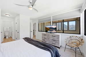 Bedroom with light wood-style flooring, connected bathroom, and ceiling fan