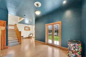 Doorway with wood finished floors, suspended lighting, and french doors