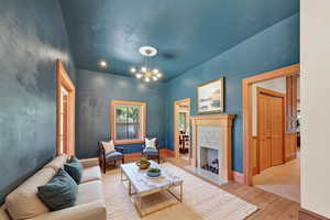 Living room featuring light wood-style flooring, a high end fireplace, and suspended lighting