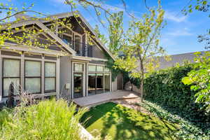 Back of property featuring a balcony, a wooden deck, and stucco siding