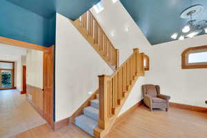 Stairs featuring wood finished floors, hanging lights, and a high ceiling