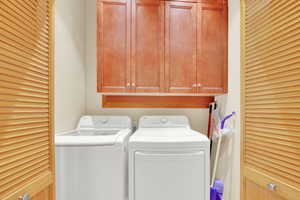 Laundry area featuring independent washer and dryer and cabinet space