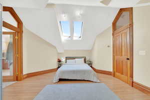 Bedroom featuring a skylight, light wood-type flooring, and lofted ceiling