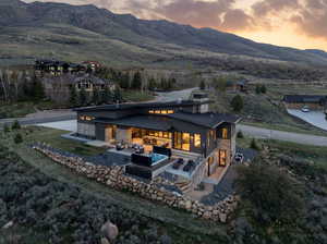 Back of property at dusk featuring stone siding, a patio area, a mountain view, and outdoor furniture