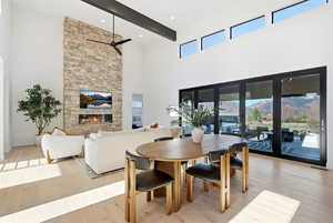 Dining area with light wood-type flooring, a fireplace, and a ceiling fan