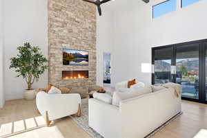 Living room with light wood-style floors, a fireplace, a high ceiling, and ceiling fan