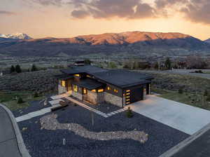 Contemporary house featuring stone siding, a standing seam roof, concrete driveway, and a mountain view