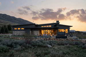 Back of property featuring a patio area, a chimney, and stone siding