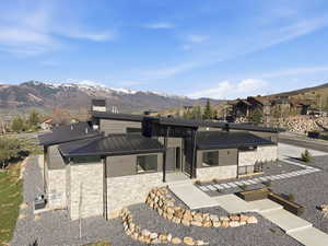 Contemporary home with stone siding, a mountain view, a standing seam roof, and a chimney