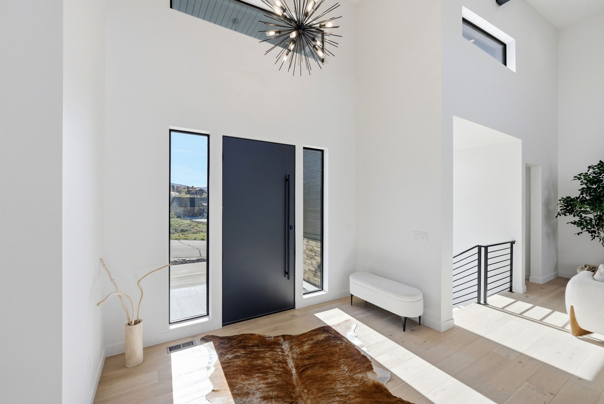 Entryway featuring plenty of natural light, hanging lights, a high ceiling, and light wood-style floors