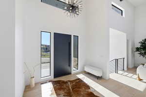 Entryway featuring plenty of natural light, hanging lights, a high ceiling, and light wood-style floors