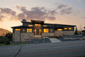 View of front of property with a standing seam roof, stone siding, a mountain view, and a chimney