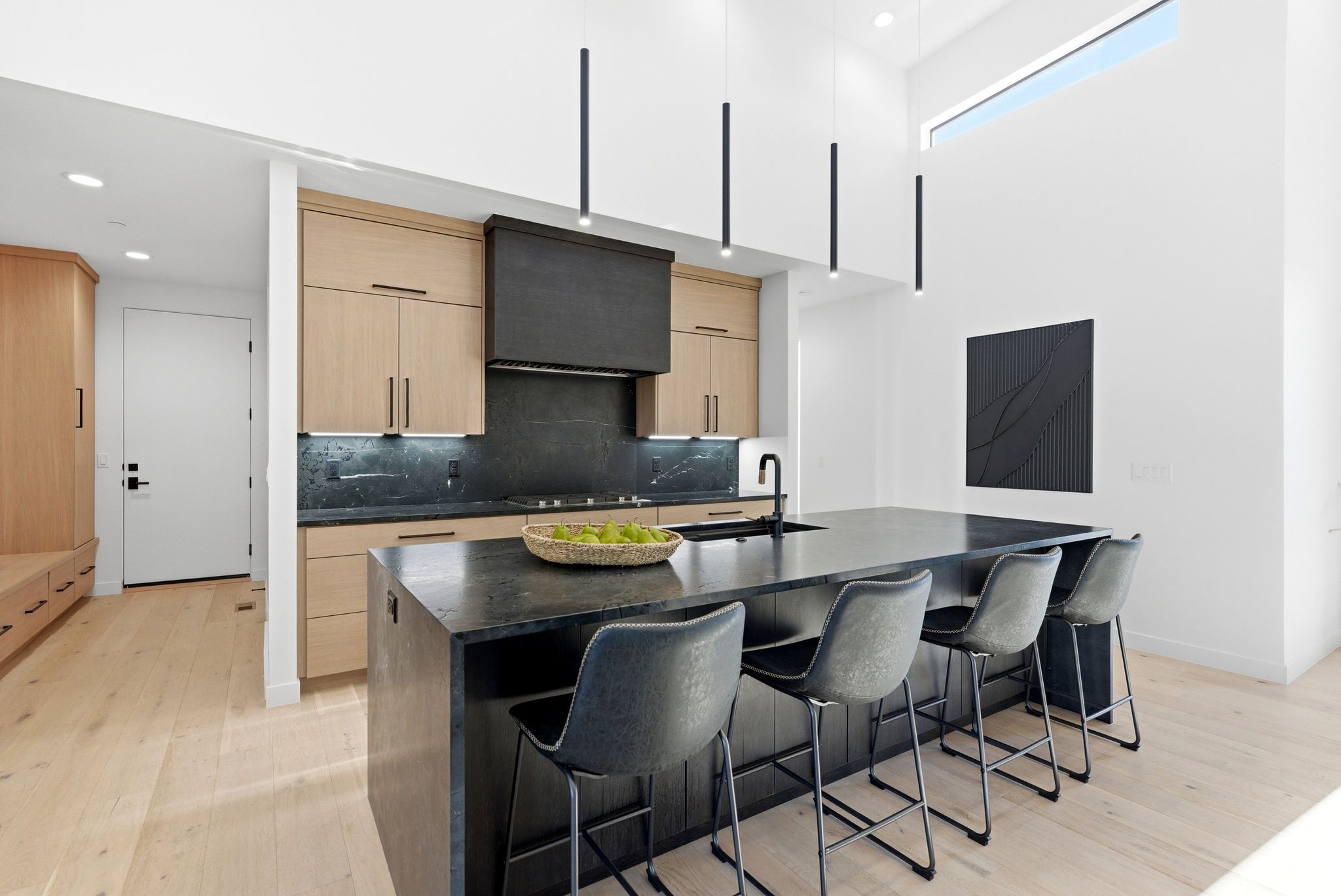 Kitchen featuring light wood finish cabinets, modern cabinets, dark stone counters, light wood-style flooring, and a breakfast bar