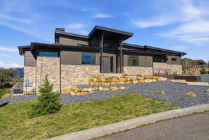 View of front of property with a front yard and stone siding