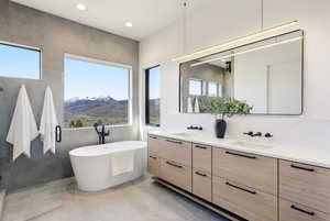 Bathroom featuring double vanity, a freestanding tub, a mountain view, recessed lighting, and light tile patterned floors
