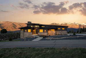 View of front of property with a standing seam roof, stone siding, a mountain view, and a chimney