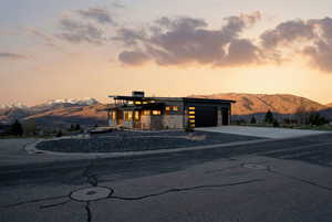 View of front of property featuring a mountain view, stone siding, a garage, and driveway