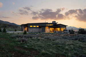 Back of house with a mountain view, a patio, stone siding, a garage, and concrete driveway