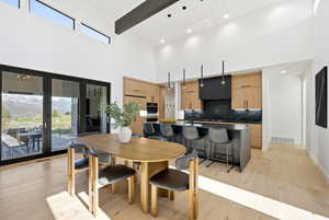 Dining space featuring light wood-style flooring, a high ceiling, and recessed lighting