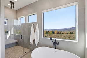 Bathroom with a soaking tub, a stall shower, and a mountain view
