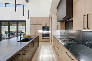 Kitchen featuring light wood finish cabinetry, dark stone counters, modern cabinets, and stainless steel appliances