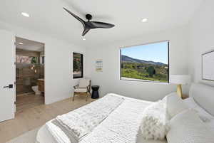 Bedroom with light wood-style flooring, ceiling fan, a mountain view, connected bathroom, and recessed lighting