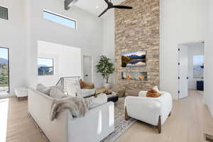 Living area with a fireplace, a high ceiling, light wood-style flooring, and ceiling fan