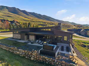 Rear view of house with a patio area, a mountain view, brick siding, a chimney, and an outdoor living space