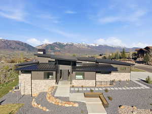 View of front facade featuring a standing seam roof, stone siding, a mountain view, and covered porch