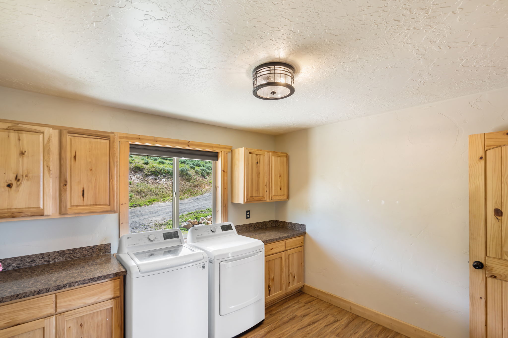 Laundry room with light wood-style floors, washing machine and clothes dryer, cabinet space, and a textured ceiling