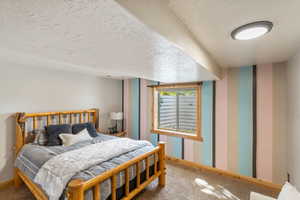 Carpeted bedroom with wallpapered walls and a textured ceiling