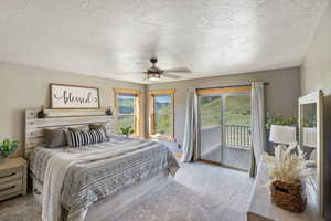 Bedroom featuring a textured ceiling, light colored carpet, access to exterior, and a ceiling fan
