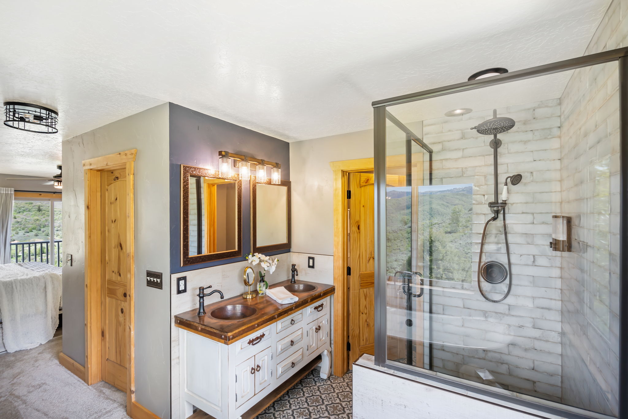 Full bath featuring ensuite bath, double vanity, a shower stall, and a ceiling fan