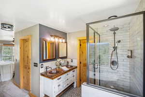 Full bath featuring ensuite bath, double vanity, a shower stall, and a ceiling fan