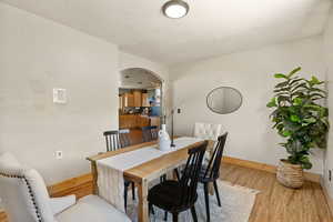 Dining space featuring arched walkways and light wood-style flooring