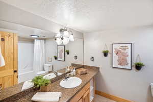 Bathroom featuring vanity, a textured ceiling, shower / bath combo with shower curtain, and light tile patterned floors