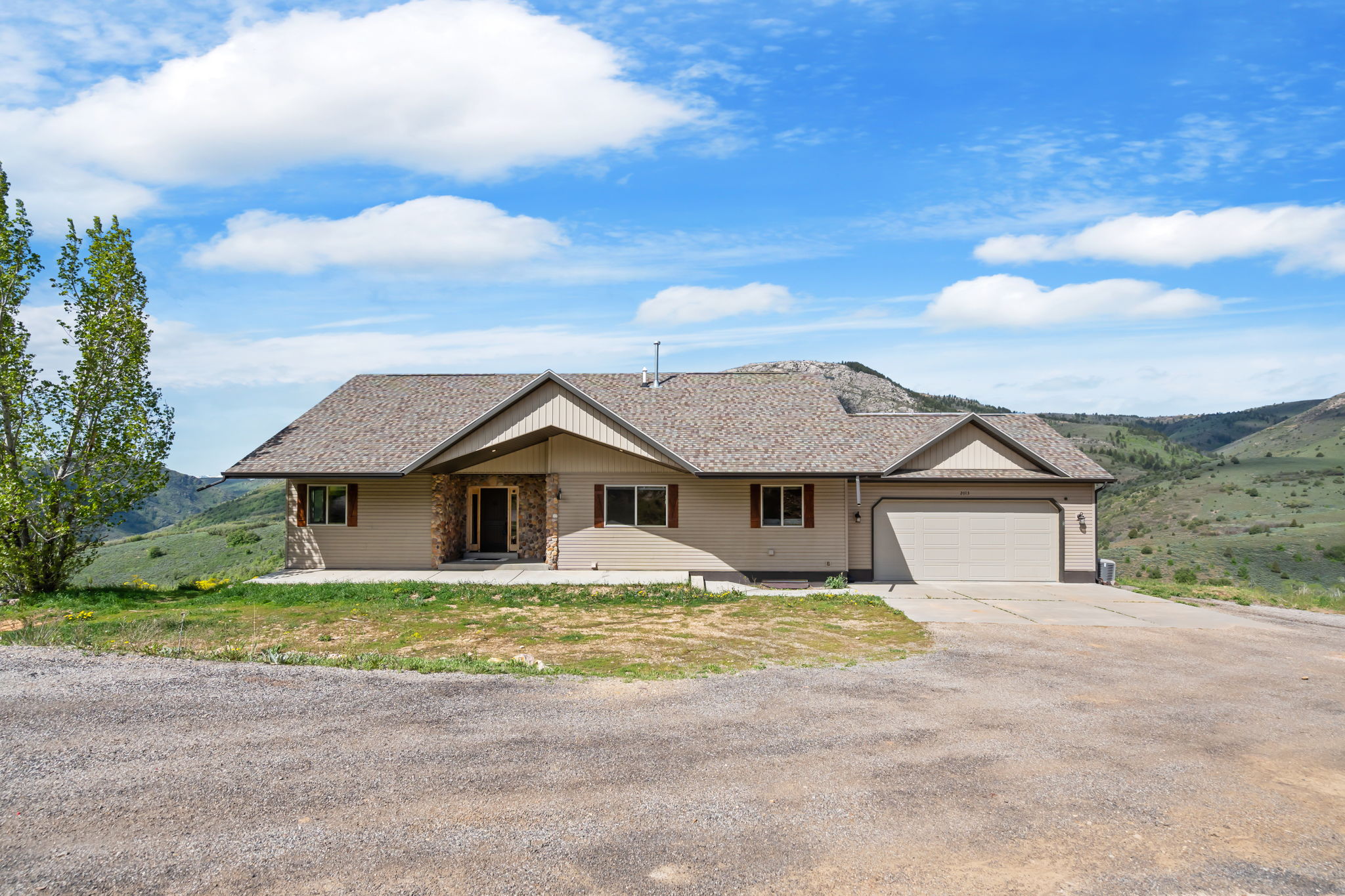 Single story home with driveway, an attached garage, and a patio