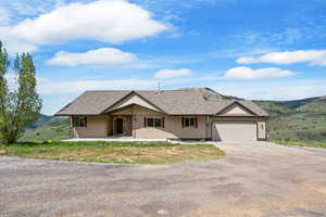 Single story home with driveway, an attached garage, and a patio